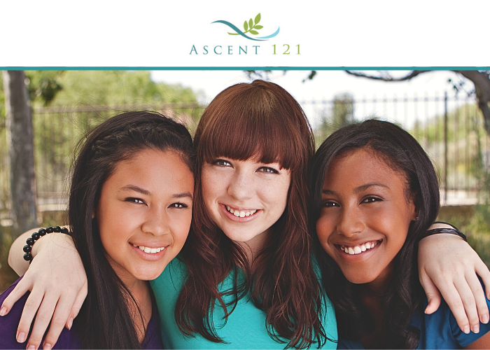 An image of a white teenager with her arms around an Asian teen and a Black teen. The girls are smiling and the Ascent 121 logo is in a white banner above their heads. The logo is a green branch with a teal curved line.