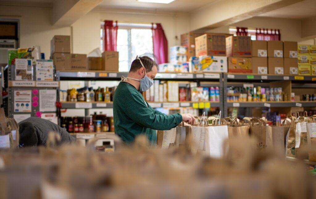 A man in a mask sorting in-kind donations at a food pantry