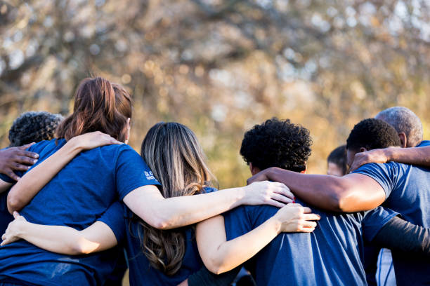 Team of diverse nonprofit volunteers huddling together during a community service event.