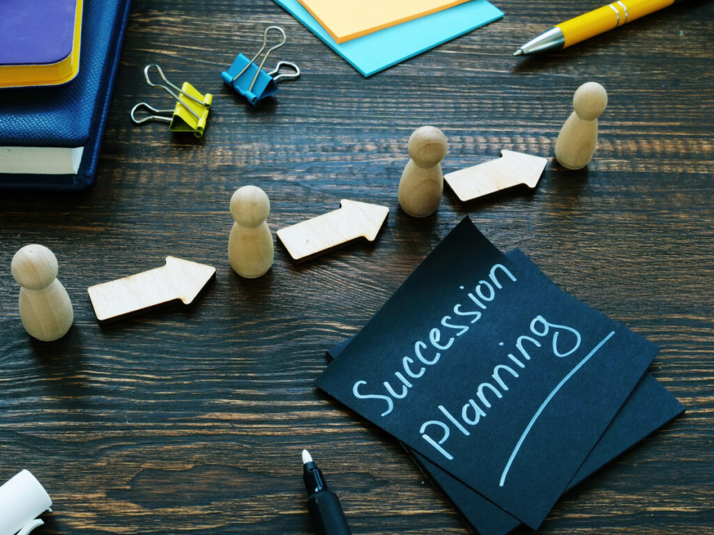 Succession planning concept with cards, wooden figures, arrows, and office supplies.